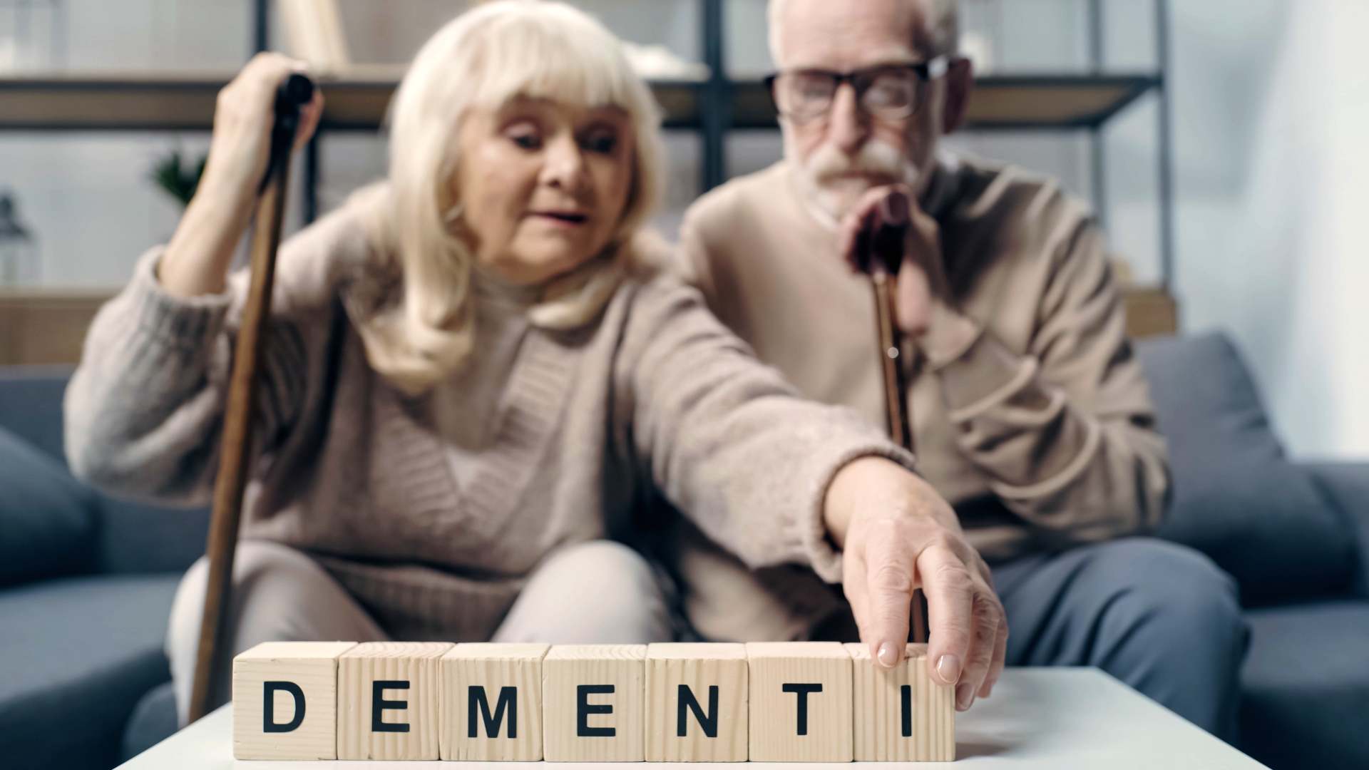 Elderly couple arranging blocks spelling “DEMENTIA.”