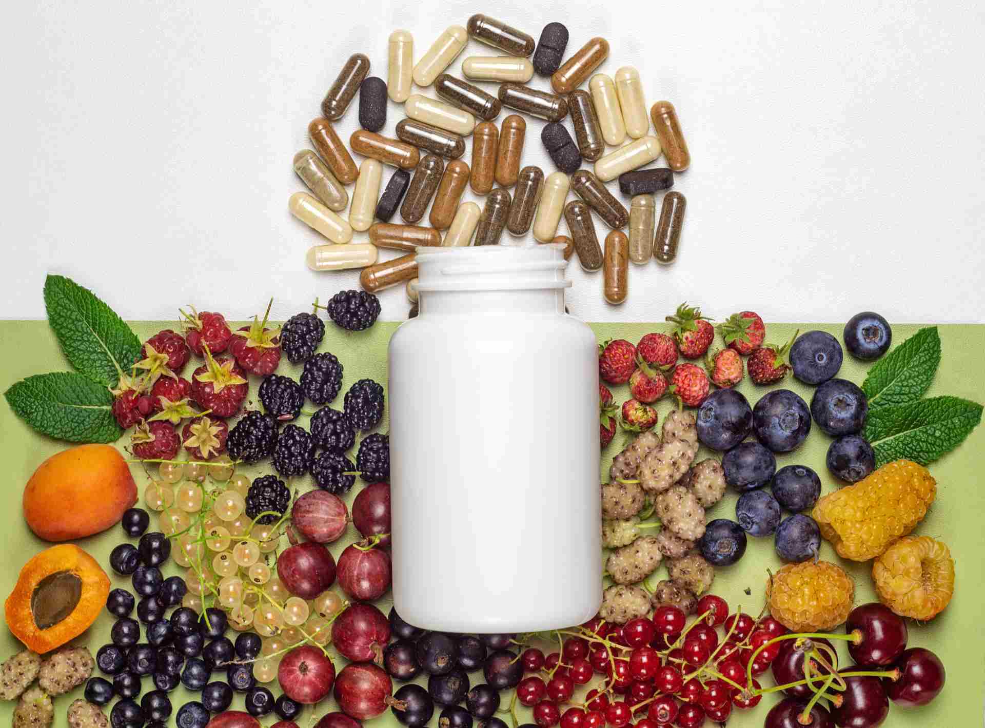 Supplement bottle surrounded by berries and capsules.