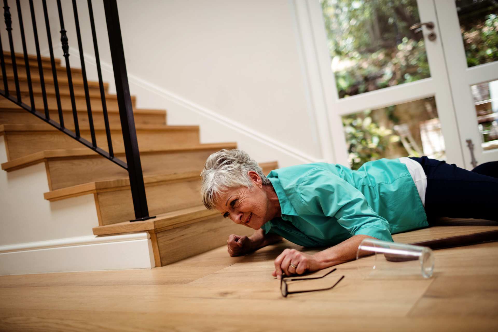 Elderly woman fallen by stairs, highlighting the risk of falls at home.