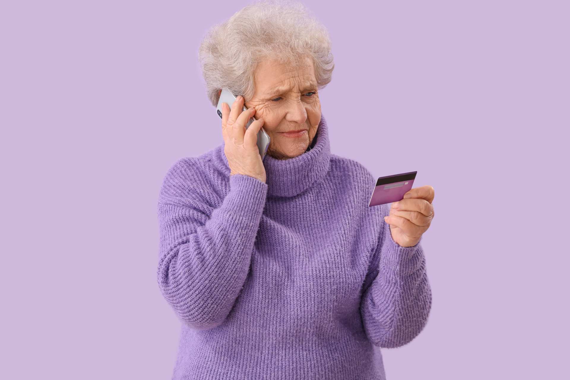 Older woman on phone with credit card, showing risks of senior financial scams.