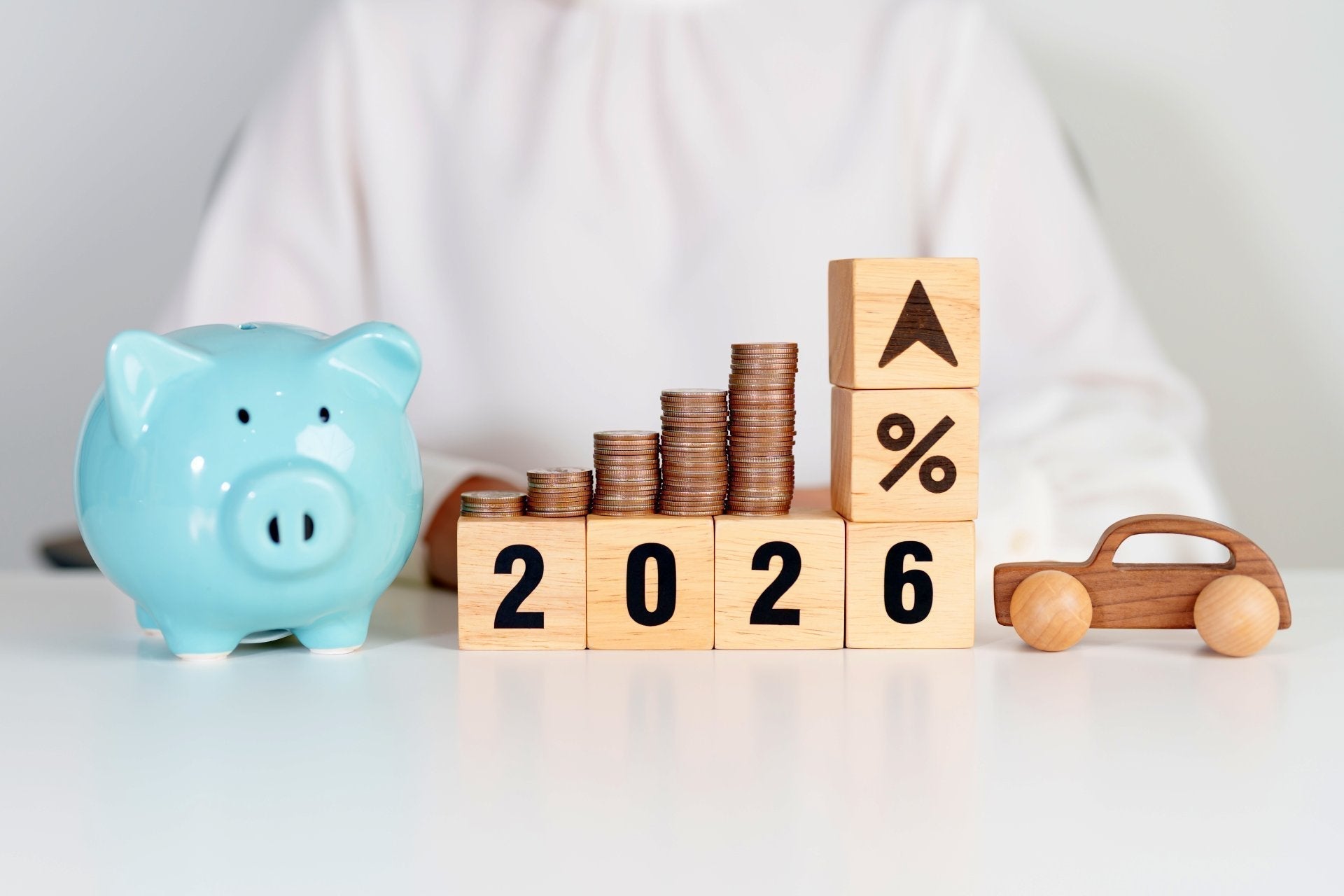 Piggy bank and stacked coins showing increasing costs in 2026.